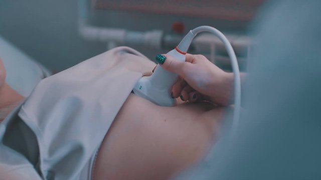 Ultrasound machine doctor s hand usg investigation USCG. Closeup of woman getting an ultrasound scan on abdominal by doctor. Young woman on ultrasound of abdominal cavity.