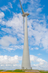 Wind turbine in a blue cloudy sky in spring