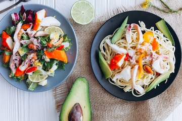 salad and pasta with seafood on wooden background 