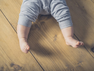 Legs and feet of a baby on the floor