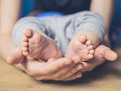 Woman cupping feet of baby