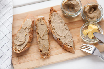 Bread with veal and rabbit pate with butter on a bamboo board. Top view