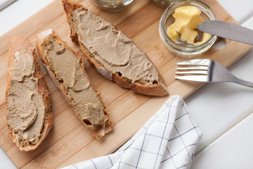 Bread with veal and rabbit pate with butter on a bamboo board. Top view
