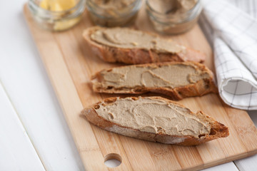 Bread with veal and rabbit pate with butter on a bamboo board