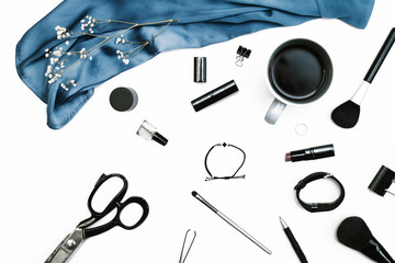 Workspace with blue cloth, scissors, coffee cup and female accessories on white background. Flat lay, top view. Feminine background