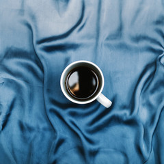 Composition with blue cloth and a coffee cup. Flat lay, top view. Morning concept