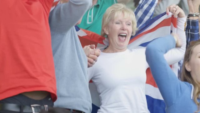  Affectionate mature couple in crowd at sports event draped in British flag