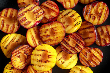 Fototapeta premium Honey glazed grilled plums on black plate