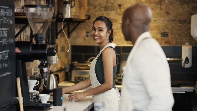  Portrait of friendly smiling worker standing behind counter in coffee shop