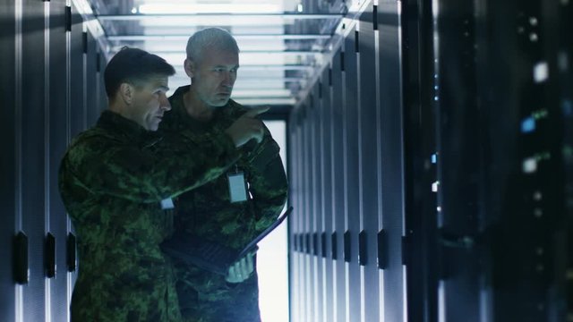 In Data Center Two Military Men Work with Open Server Rack Cabinet. One Holds Military Edition Laptop.  Shot on RED EPIC-W 8K Helium Cinema Camera.