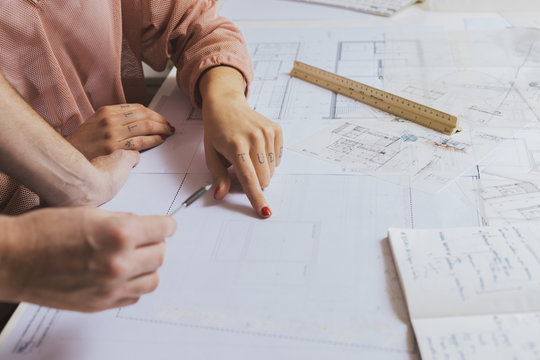 Hands of workers discussing blueprint