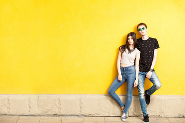 Obraz na płótnie Canvas Couple posing in fashion style on yellow wall. Lifestyle and relationship