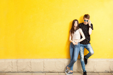 Fototapeta na wymiar Young couple posing in fashion style on yellow wall. Lifestyle and relationship