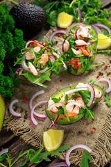 Avocado boats stuffed with salmon, red onion and arugula. concept healthy food