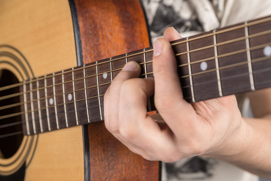 A picture of an acoustic guitar, classical color, in the hands of a guitarist