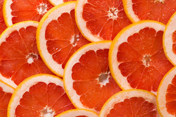 Bright red background with juicy slices of grapefruit. Healthy food background.