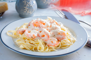 Italian pasta fettuccine in a creamy sauce with shrimp close-up on a plate. horizontal