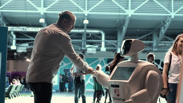Modern Robotic Technologies. A man communicates with a robot, presses a plastic mechanical arm to the robot, handshake.