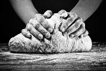 Mains de femme pétrissant la pâte. Dans un style noir et blanc sur fond sombre.