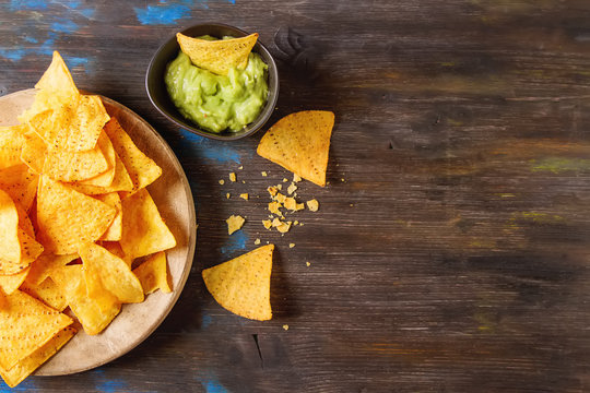 Snack for a party, chips with a tortilla, nachos with sauces: guacamole. Mexican food. Dark background. Top view. Copy space