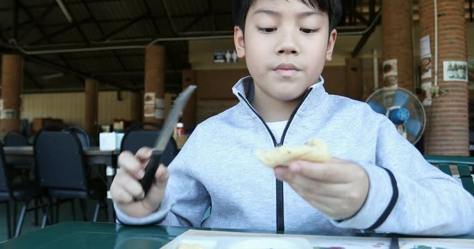 Close up asian boy enjoy eating food at restaurant