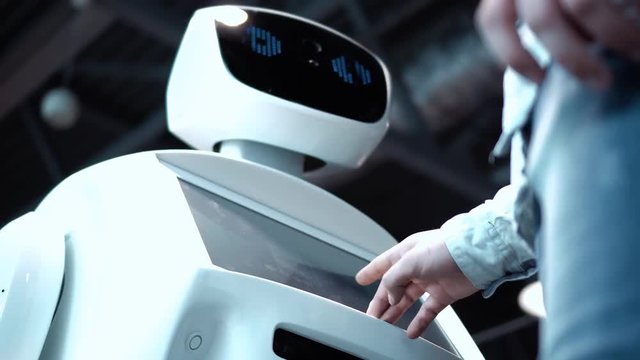 Modern Robotic Technologies. A man communicates with a robot, presses a plastic mechanical arm to the robot, handshake.