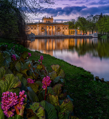Pałac na Wyspie, Łazienki Królewskie. A Neoclassicist palace in Warsaw - night view with flowers and lake reflection - 144713118