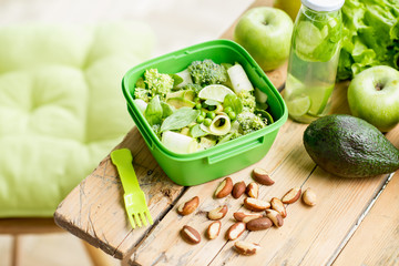 Salad with tomatoes and cheese in the bowl on the wooden table with green healthy ingredients. Healthy food concept