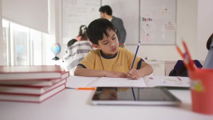  Portrait of happy little boy working at his desk in school classroom - Powered by Adobe