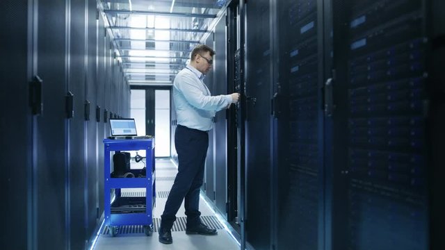 IT Engineer Taking Hard Drives off the Crash Cart and Installing Them into Rack Server. He's Working in Data Center. Shot on RED EPIC-W 8K Helium Cinema Camera.