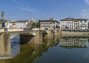 Obraz premium The Ponte alle Grazie bridge is reflected in the Arno river which flows in the historic center of Florence, Italy, on a sunny day