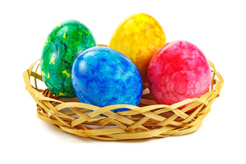 Red, green, blue and yellow Easter egg in basket on a white background