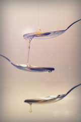 Honey pouring from spoon against a light background