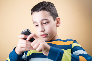 Boy sitting and playing with mobile phone.