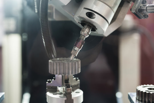 The five-axis Computer Numerical Control (CNC) machine while cutting sample gear part. Indutrial machine.