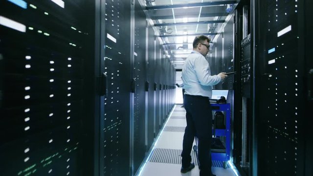 Footage of Camera Moving Through Opening Sliding Doors Past IT Engineers Working. Shot on RED EPIC-W 8K Helium Cinema Camera.