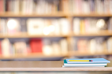 Notebook paper and pencil on table over blur book store background, with copy space for display montage, education concept