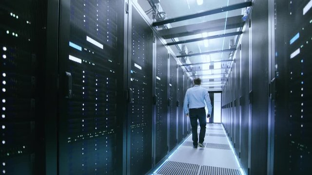 Elevating Shot In Data Center. Starts From Underground then Elevates to The Glass Ceiling. Rows of Server Racks in this Data Server are Visible. IT Engineer Working There. Shot on 8K UHD Camera.