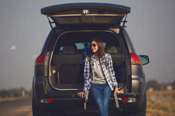 Asia Woman traveler sitting on hatchback car with backpack