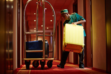 Hotel servant taking out suitcase with baggage from hotel room