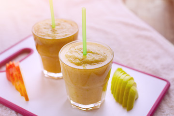 Two smoothies of apples, pears, oranges, bananas, stand on the white Board