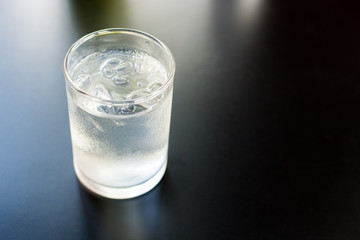 A glass of water with iced on dark background