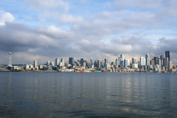 Naklejka premium SEATTLE, WASHINGTON, USA - JAN 25th, 2017: A view on Seattle downtown from the waters of Puget Sound. Piers, skyscrapers, Space Needle and Ferris wheel in Seattle city before sunset