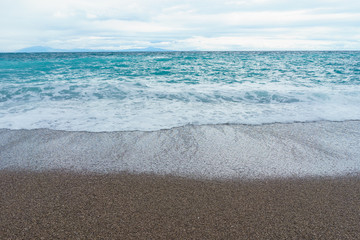Fototapeta na wymiar selective focus Soft and gentle waves foam in blue ocean italy coast, summer evening as background