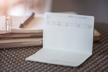 Saving money, empty book bank with revenue expenditure memo background on desk