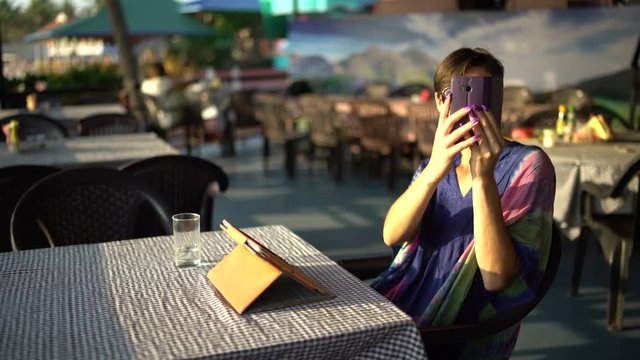 Girl is sitting in a cafe and making selfie on the phone