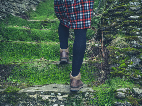 Woman in skirt walking up steps in nature