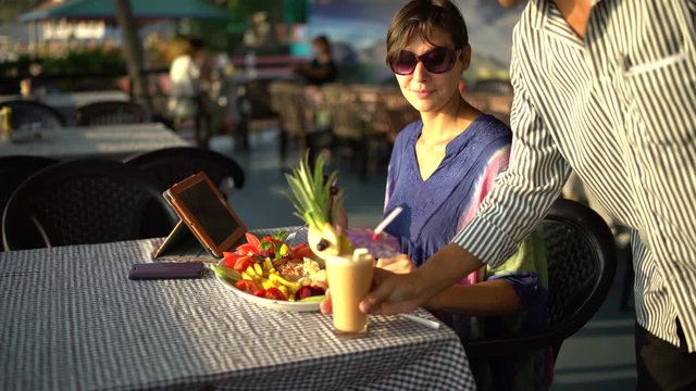 Waiter brings a cocktail and puts on the table