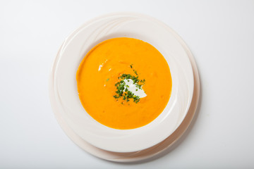 Homemade pumpkin soup with cream with spices on white plate