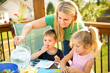 Dinner: Mother Pours Water Into Glasses For Children